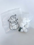 Child assembling a snowman using cotton balls in the Snowman Bag Activity from the baking kit.