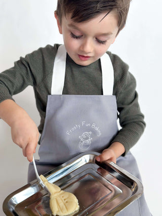 Preschool-aged child wearing an apron, using baking tools from the Frosty Fun Baking Kit