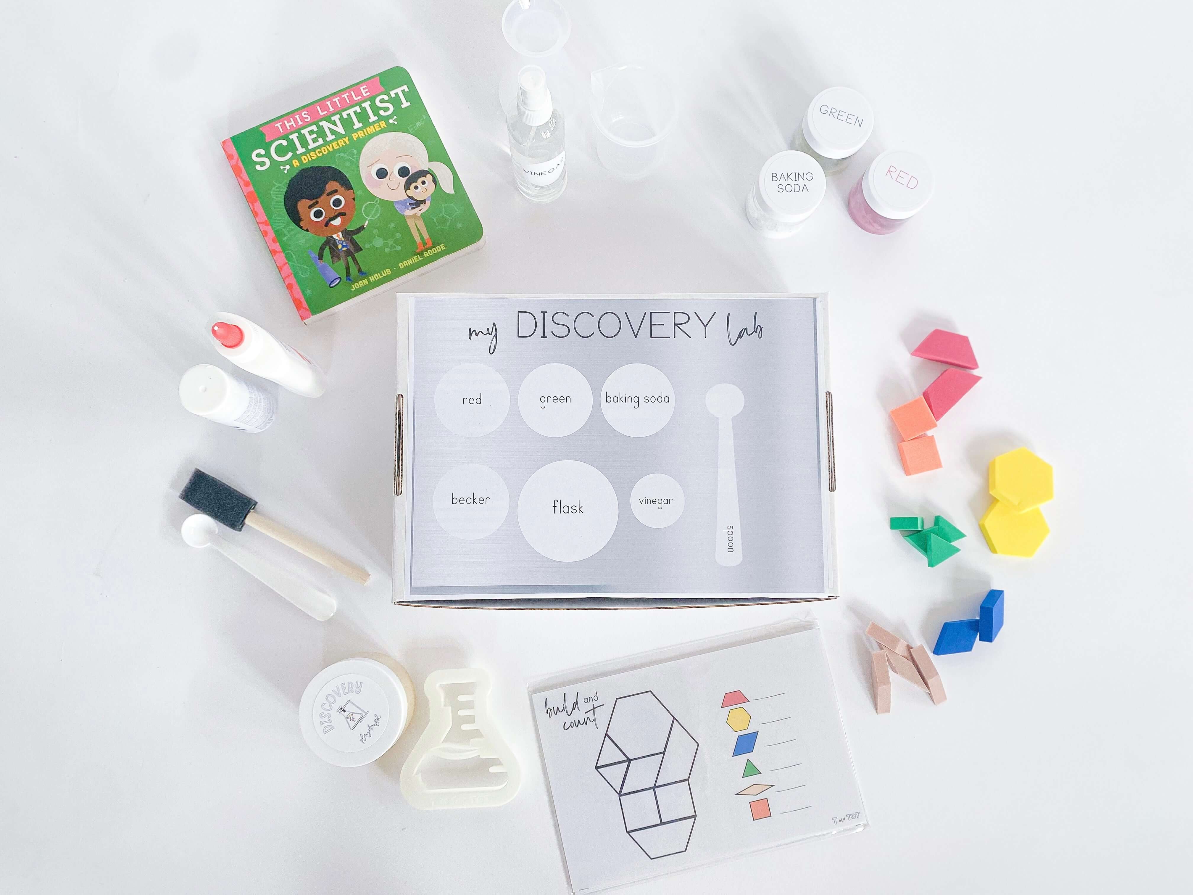 Play-based Discovery Kit for kids, including homemade playdough, custom flask playdough cutter, and science experiment materials. Includes a Little Scientist board book, art experiment supplies, and a detailed brochure with instructions.