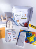 Interactive play kit for kids with construction plans, building blocks, homemade playdough, and a brick playdough roller. Includes role play items such as a blueprint, caution tape, and building permit, plus a blueprint journal with colored pencils."
